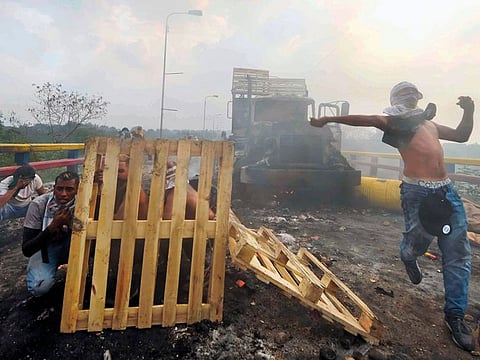 Demonstrators protect themselves after a truck was set on fire at the international bridge linking Cucuta, Colombia, and Urena, Venezuela on Saturday.
