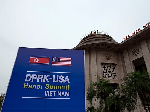 Vietnamese soldiers watch from a top of a building neighboring Government Guesthouse and the Metropole hotel next to a poster featuring upcoming summit between the U.S. and North Korea in Hanoi, Vietnam, Sunday, Feb. 24, 2019.