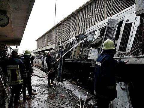 Firefighters hose down a train that was damaged after a crash inside Ramsis train station in Cairo, Egypt, Wednesday, Feb. 27, 2019.