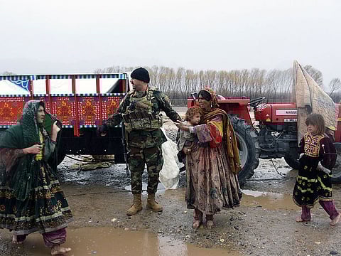 Afghan Security forces help a woman and child after flood affected their homes in Arghandab district of Kandahar province, on March 2, 2019