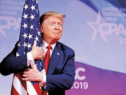 US President Donald Trump hugs American flag at the Conservative Political Action Conference (CPAC) annual meeting at National Harbor near Washington, on March 2, 2019.