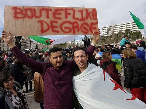 A demonstrator holds up a placard that reads, "Bouteflika go away" during a protest to denounce President Abdelaziz Bouteflika's bid for a fifth term