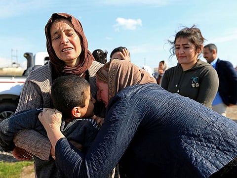 Relatives hug a Yazidi survivor boy following his release from Daesh militants in Syria