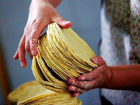 An employee arranges a stack of freshly made corn tortillas at a tortilla factory in Mexico City.