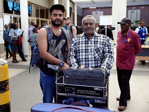 Passenger Ahmed Khalid (L), who missed his Ethiopian Airlines Flight ET 302 while connecting from Dubai, is received by his father Khalid Bzambur (R) at the Jomo Kenyatta International Airport (JKIA) in Nairobi, Kenya