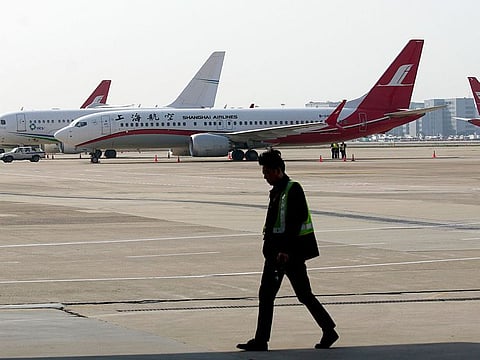 A ground crew walks near a Boeing 737 Max 8 plane operated by Shanghai Airlines parked on the tarmac at Hongqiao airport in Shanghai, China, Tuesday, March 12, 2019.