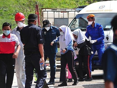 Emergency personnel help students school evacuate after toxic chemical spill in Pasir Gudang, Johor state on Wednesday, March 13, 2019. Malaysia's education ministry has ordered 34 schools to be closed in southern Johor state after toxic waste believed dumped in a river sickened dozens of students and teachers.