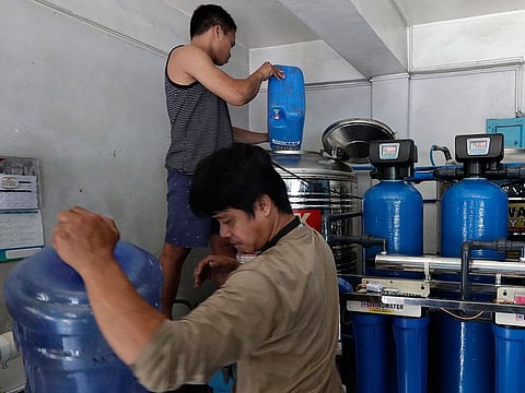 Workers prepare to filter water at a purifying station while they wait for the water supply to return at their area in Mandaluyong, metropolitan Manila, Philippines.