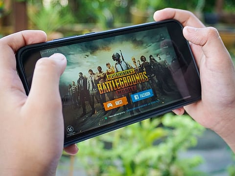 A player holding a smartphone with Player's Unknown Battleground, also known as PUBG online shooting gaming.