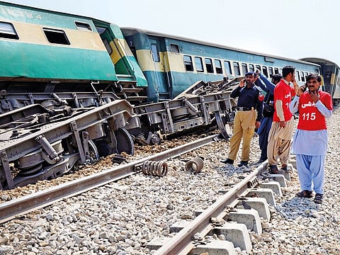 A police officer and rescue workers stand near the derailed train. There was no immediate claim of responsibility, but ethnic Baloch separatists have attacked trains in the past.