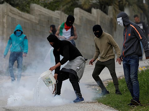 A Palestinian protester sprays water at a tear gas canister during clashes with Israeli forces near Ramallah, in the Israeli-occupied West Bank.