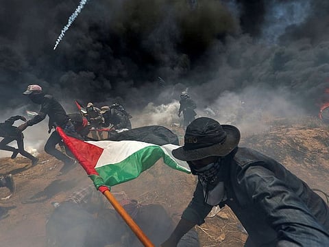 Palestinian demonstrators run for cover from Israeli fire and tear gas during a protest at the Israel-Gaza border in the southern Gaza Strip
