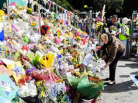 A woman lays flowers for the victims of the Christchurch terrorist attack outside the Kilbernie Mosque in Wellington, New Zealand, on Friday, March 22, 2019. Radio and television stations across New Zealand broadcast the Muslim call to prayer followed by two minutes of silence as the nation stopped to honor the 50 people killed and more than 40 wounded in last week's mosque attacks.