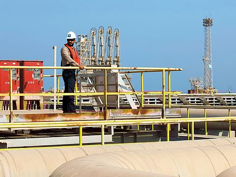 An employee looks out across oil pipes used for landing and unloading crude and refined oil at the North Pier Terminal, operated by Saudi Aramco, in Ras Tanura, Saudi Arabia.