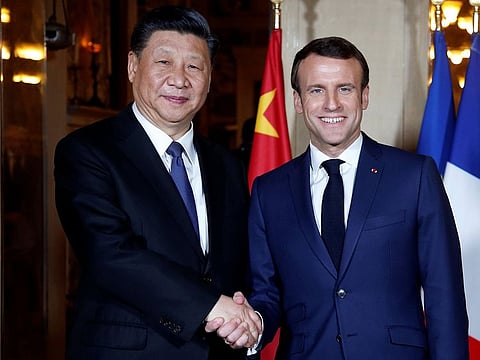 French President Emmanuel Macron (R) shakes hand with China's President Xi Jinping.