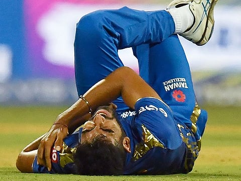 Mumbai Indians's Jasprit Bumrah clutches his shoulder in pain after a tumble during the IPL T20 cricket match against Delhi Capitals at The Wankhede Stadium in Mumbai on March 24, 2019.
