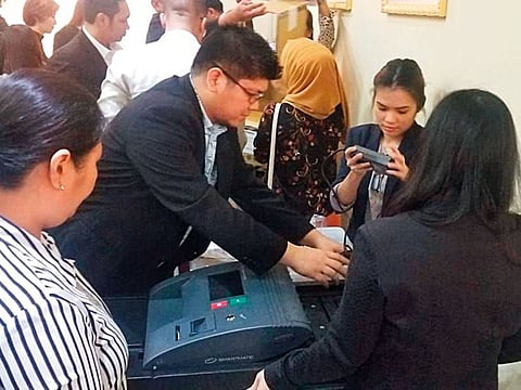Philippine Consulate General Dubai staff with a vote-counting machine during last-minute checks ahead of the elections.
