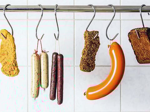 Vegan and vegetarian sausages and steaks hanging on hooks.