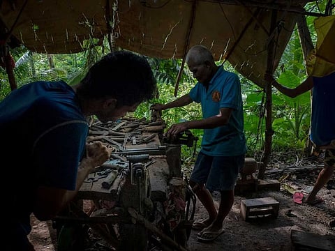 A gunsmith crafting a .45-caliber pistol by hand in a hut in the woods near Danao, the Philippines.