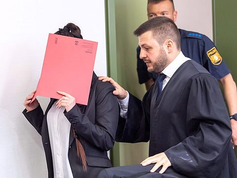 Defendant Jennifer W (L) hides her face behind a folder and walks next to her lawyer Ali Aydin (R) as she arrives at court for the opening of her trial on April 9, 2019 in Munich, southern Germany.