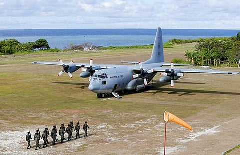 This photo, taken on April 21, 2017, shows troops marching as a Philippine Air Force C-130 transport plane carrying Defense Secretary Delfin Lorenzana sits on the tarmac of Pagasa (Thitu) Island on the disputed Spratlys chain of island in the West Philippine Sea. Lorenzana visited the island with then Armed Forces Chief Gen. Eduardo Año and other officials.