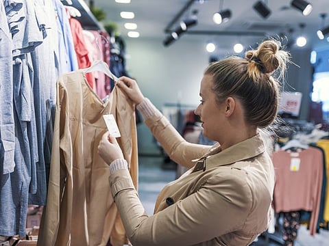 Portrait of Caucasian beautiful woman  looking for clothes in store. Waist photo of  Happy Young Woman Looking at Clothes Hanging on the Rail Inside the Clothing Shop. businesswoman buying clothes.