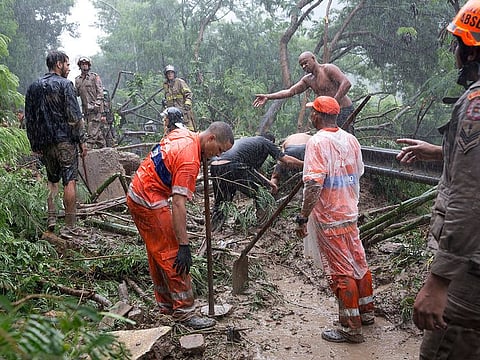Rescue workers and residents search for survivors where heavy rains caused a landslide half-burying several vehicles and uprooting trees, in Rio de Janeiro, Brazil, Tuesday, April 9, 2019.