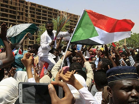 Young Sudanese wave their national flag as they rally to celebrate after an announcement made by Sudan's new military ruler, outside the army headquarters in the Sudanese capital Khartoum