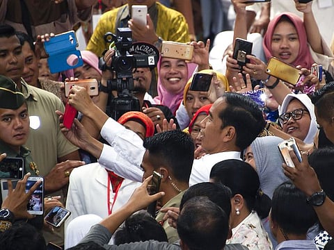 This picture taken on April 3, 2019 shows Indonesia's President Joko Widodo (C) taking a selfie with his supporters during an election campaign stop in Sragen, Central Java province. Indonesia's heavy metal-loving leader Joko Widodo faces off against ex-military general Prabowo Subianto in the race to lead the world's third-biggest democracy on April 17, a re-run of the 2014 election contest narrowly won by Widodo.