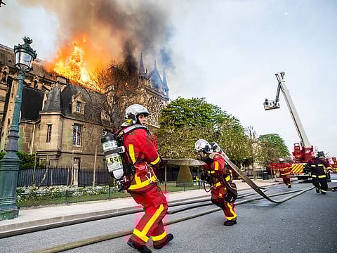 Paris fire brigade members work outside the Notre Dame-Cathedral, after the fire broke out.