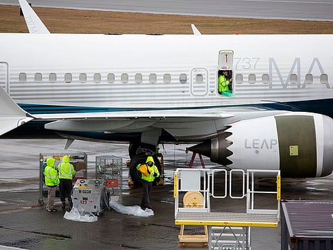 Workers are pictured next to a Boeing 737 MAX 9 airplane on the tarmac at the Boeing Renton Factory in Renton, Washington.