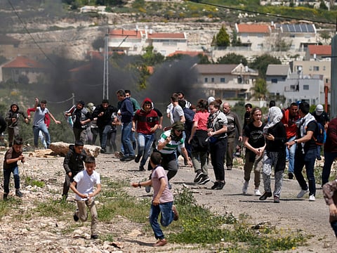 Palestinian protesters run for cover during a weekly demonstration against the expropriation of Palestinian land by Israel, in the village of Kfar Qaddum, near Nablus in the occupied West Bank, on April 12, 2019.