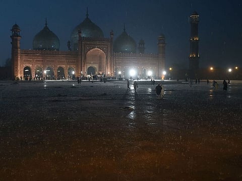 People arrive to pray at the historical Badshahi Mosque during heavy rain in Lahore.