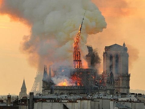 Flames and smoke rise from the blaze as the spire starts to topple on Notre Dame cathedral in Paris, Monday, April 15, 2019.