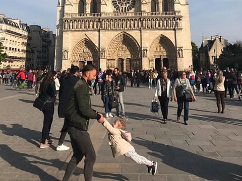 Father plays with a child outside the Notre-Dame Cathedral
