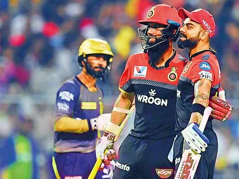 Royal Challengers Bangalore's cricketers Moeen Ali and Virat Kohli (R) celebrate as Kolkata Knight Riders's captain Dinesh Karthik(L) looks on during the IPL match between them at the Eden Gardens Cricket Stadium, in Kolkata on April 19, 2019.