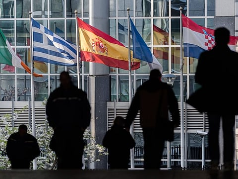 National flags of European Union (EU) member states fly from flag poles outside the European Parliament building in Brussels, Belgium.