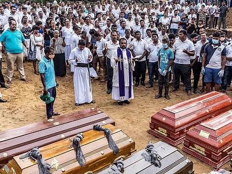 A priest officiates at a mass burial near St. Sebastian's Church in Negombo, Sri Lanka, on Wednesday, April 24, 2019.