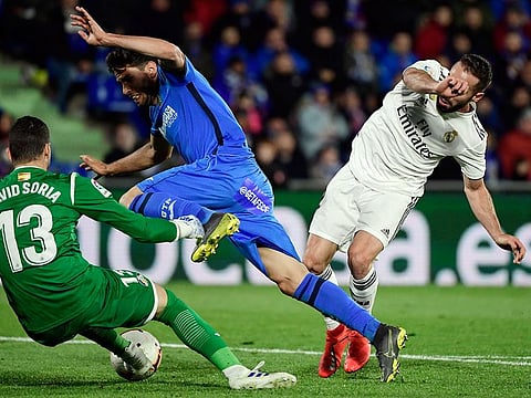 Real Madrid defender Dani Carvajal, centre, vies with Getafe's defender Bruno Gonzalez and goalkeeper David Soria.