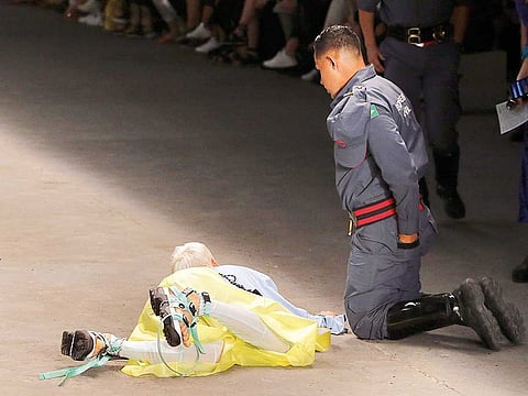 Model Tales Soares lies on the catwalk as a paramedic tends to him after he collapsed during Sao Paulo Fashion Week in Sao Paulo, Brazil