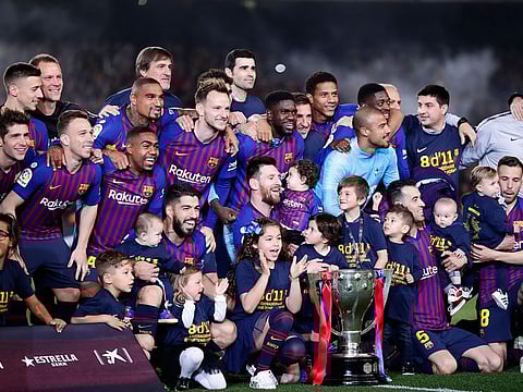 FC Barcelona players, with their children, pose with the trophy after winning the Spanish League title, at the end of the La Liga match against Levante at the Camp Nou stadium in Barcelona, on Saturday.