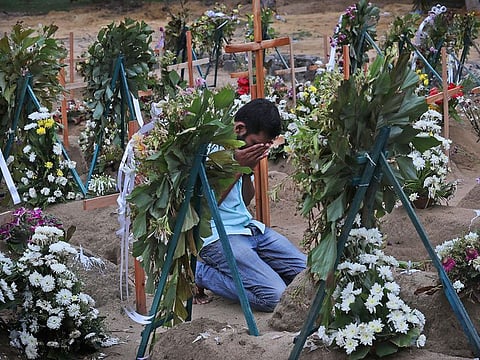 A relative of a victim of the Easter Sunday bomb blasts pays tribute in the cemetery after a televised Sunday mass by Archbishop Malcolm Ranjith in Negombo, Sri Lanka.