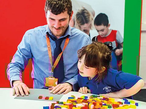 Children playing with Lego bricks featuring the shapes of Braille dots and the corresponding letter, number or punctuation symbol.