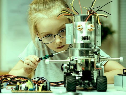 Little girl assembling a robot