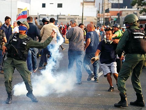 A military member throws a tear gas canister near the Generalisimo Francisco de Miranda Airbase ‘La Carlota’, in Caracas, Venezuela, on Tuesday.