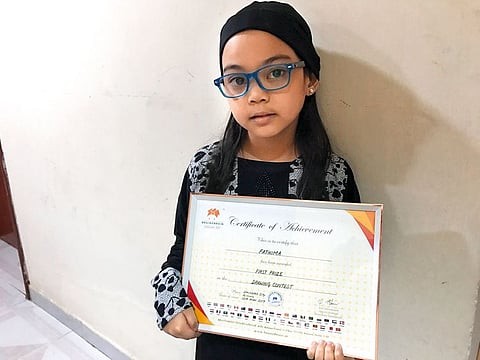 Fatima holds up a certificate she won in a drawing contest. She hopes to join a school, perfect her art and make friends.