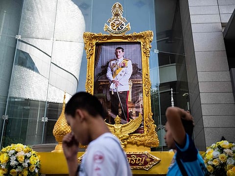 People walk past a portrait of Thailand's King Maha Vajiralongkorn in Bangkok on May 1, 2019, ahead of his coronation which will take place from May 4 to 6