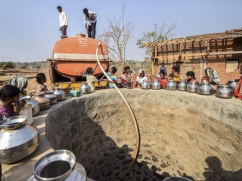 A government tanker releases water into a well as villagers wait to fill their containers in a village in Maharashtra, India.