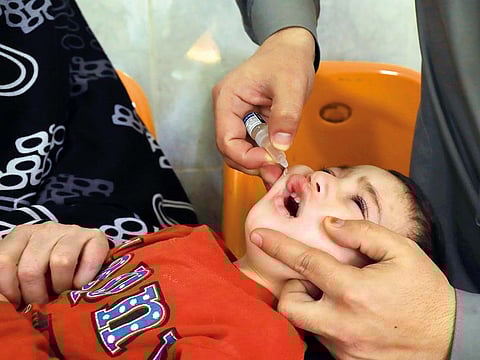 A boy receives polio vaccine drops from health workers at a booth outside a hospital in Peshawar, Pakistan.