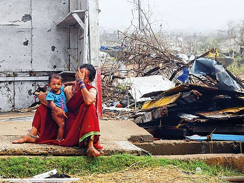 A woman sits with her child next to storm-damaged buildings in Puri in the eastern Indian state of Odisha, after Cyclone Fani swept through the area.